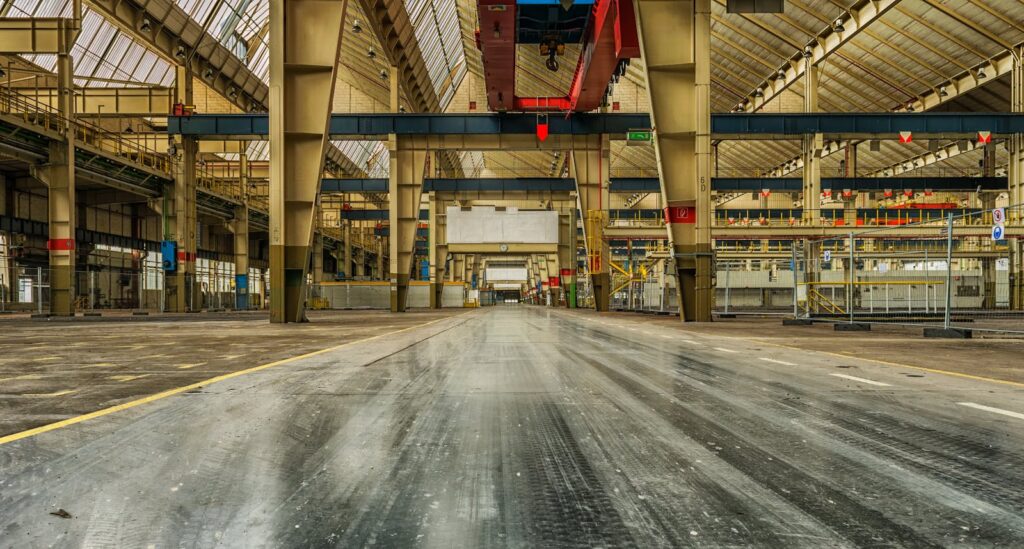 Wide view of an empty industrial manufacturing warehouse with visible cranes and metal structures.