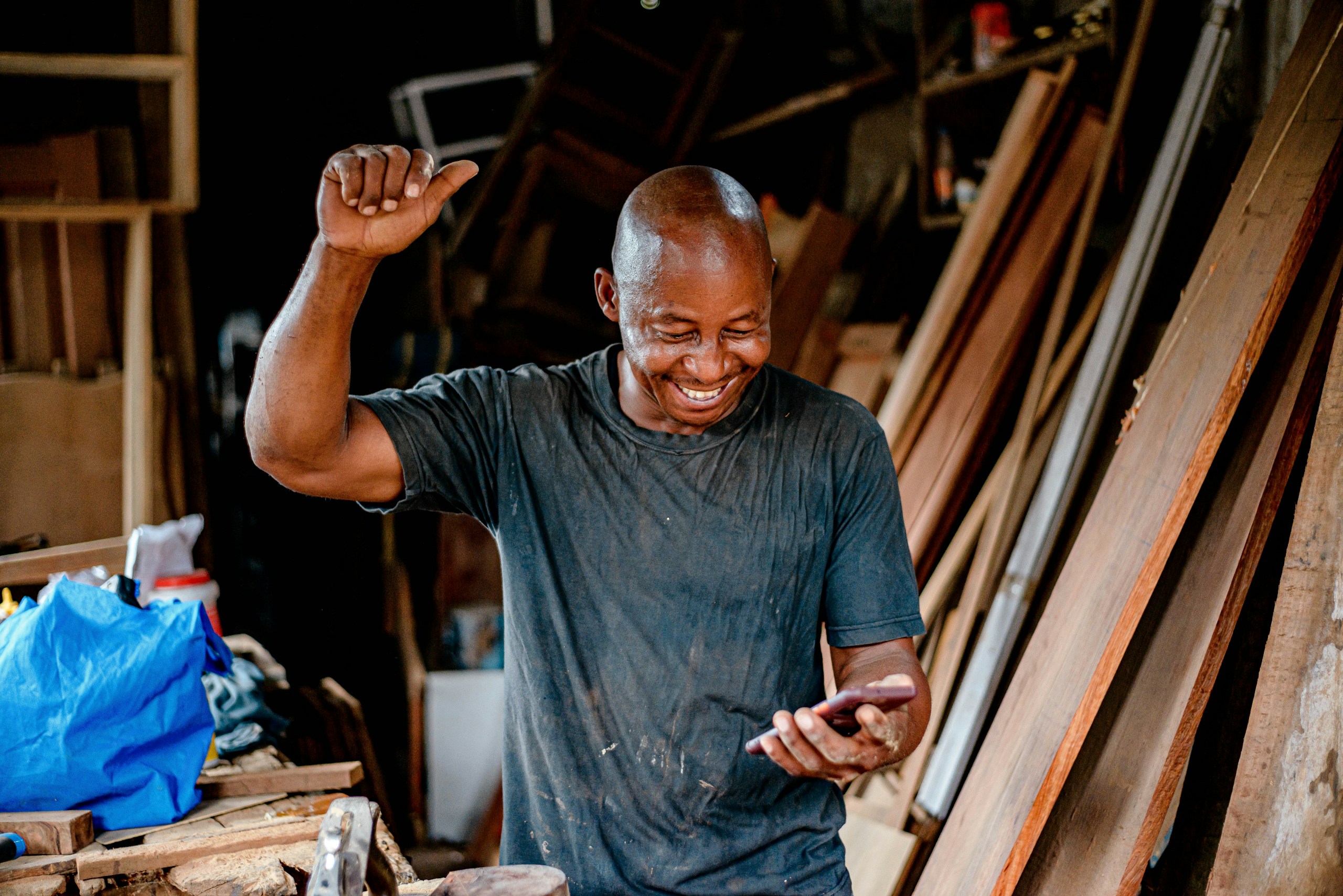 MSME business of an African Carpenter using his smartphone happy celebrating