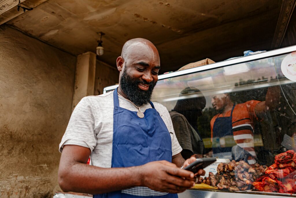 African street food vendor using a smartphone